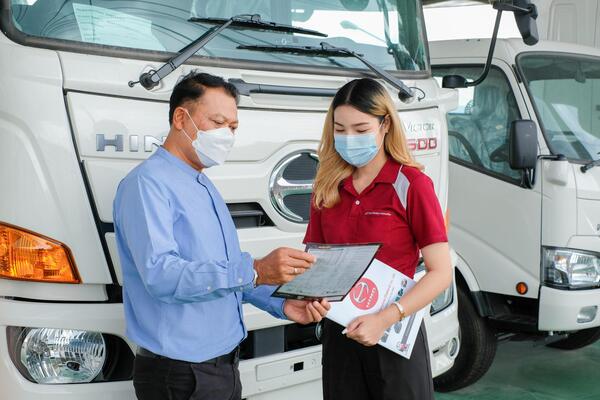  Professional mechanic inspecting used semi-truck PTO system, hydraulic components, and transmission connection before purchase